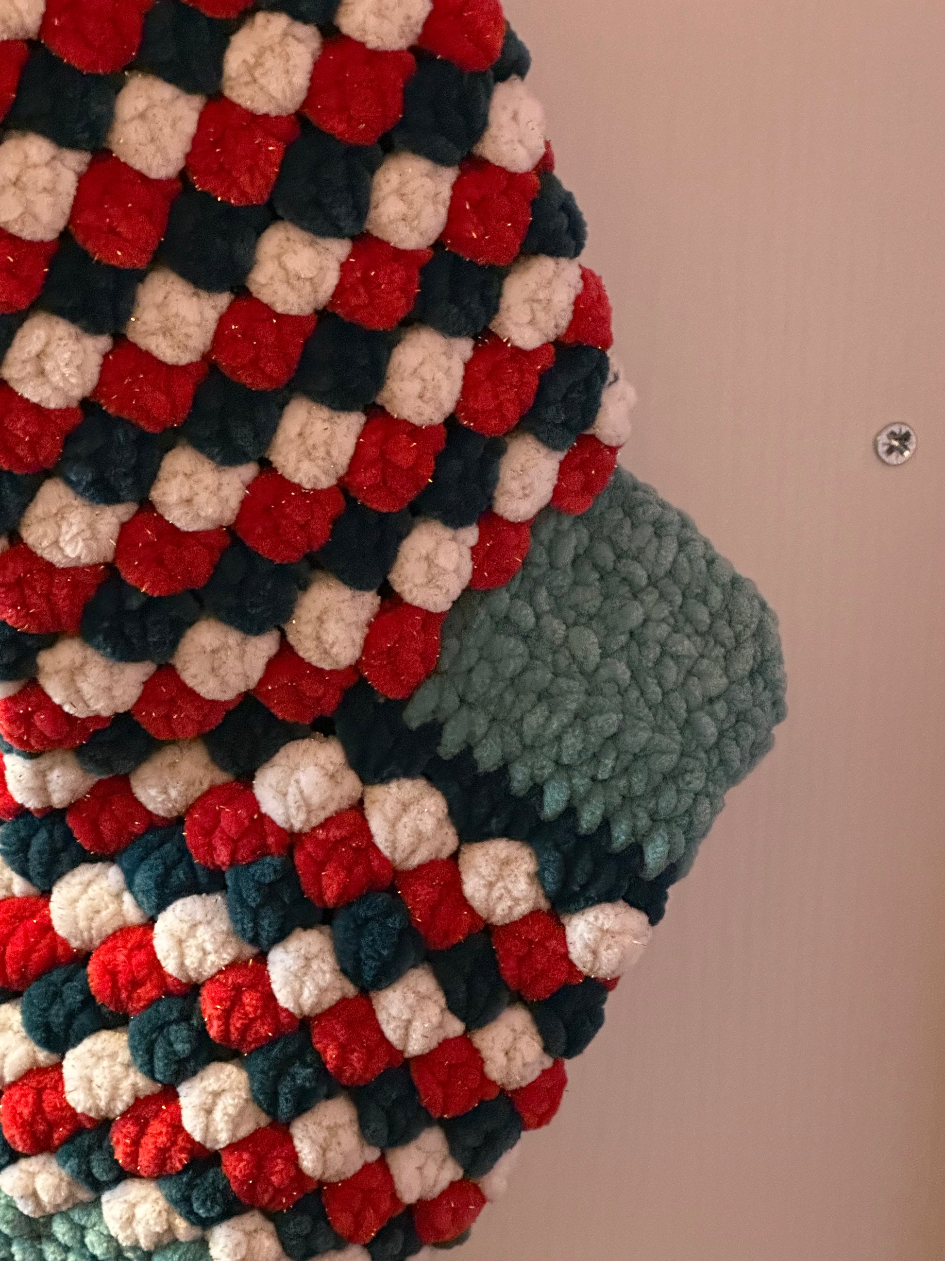 Textured fabric with a checkered pattern in red, green, and beige on a neutral background