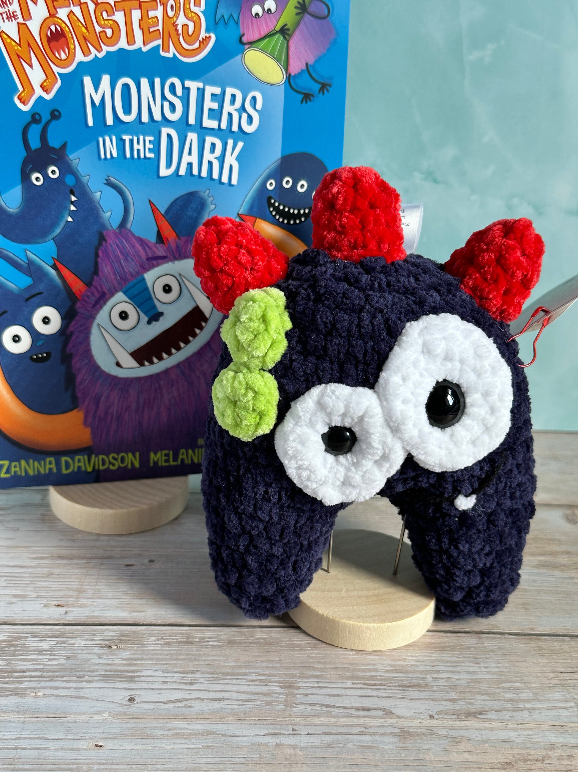 A close up of a Navy Monster with Red horns with the Billy and the Mini Monsters Book in the background
