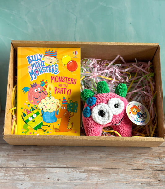 Pink Monster and Book presented in a cardboard box on pastel shedded paper.